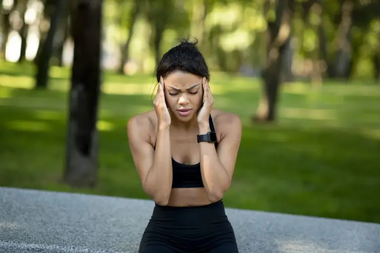 black woman jogger having headache during training at park