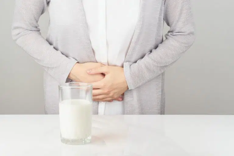 woman next to glass of milk having bad stomach ache