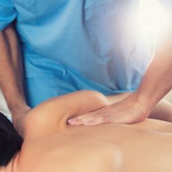 Physiotherapist doing healing treatment on man's back. Therapist wearing blue uniform. Osteopathy. Chiropractic adjustment, patient lying on massage table